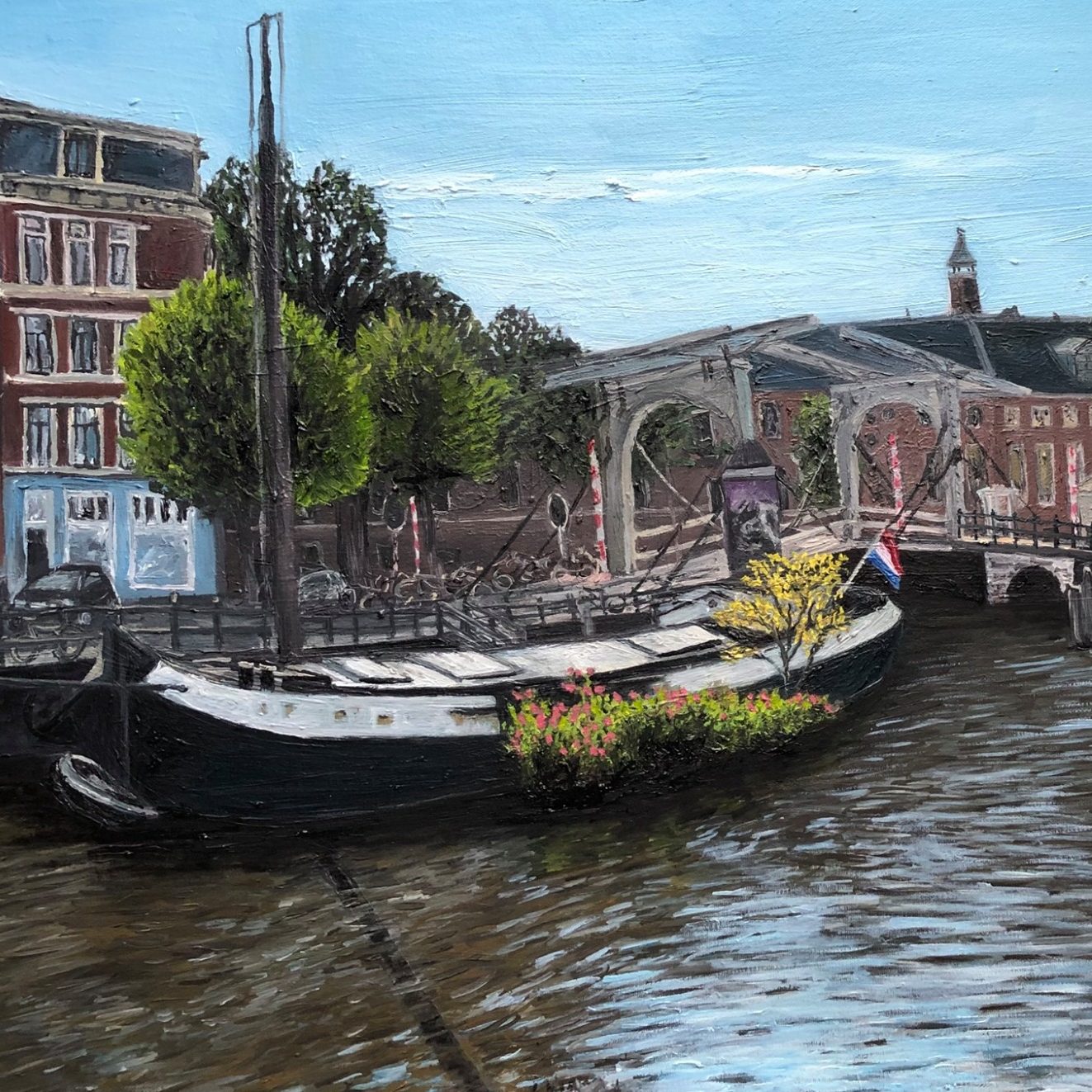 A Boat in Amsterdam A moored Canal boat in Amsterdam with flowers, surrounded by buildings and trees by a river.