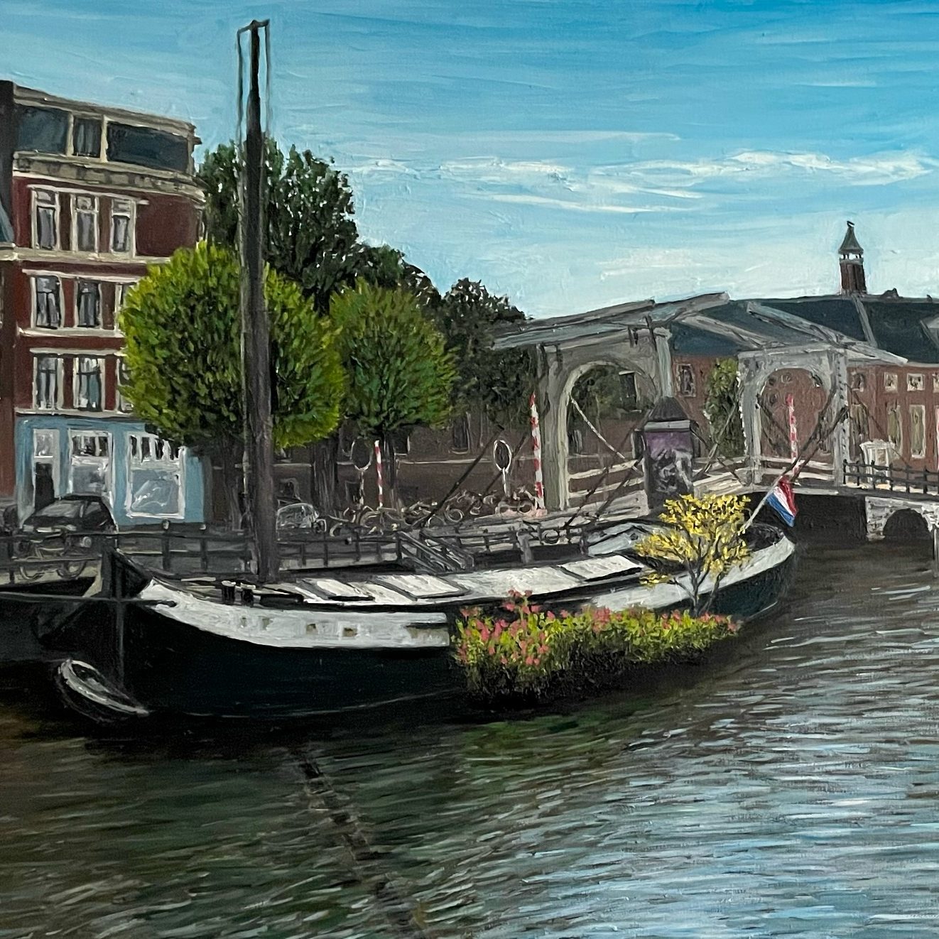 A Boat in Amsterdam A moored Canal boat in Amsterdam with flowers, surrounded by buildings and trees by a river.